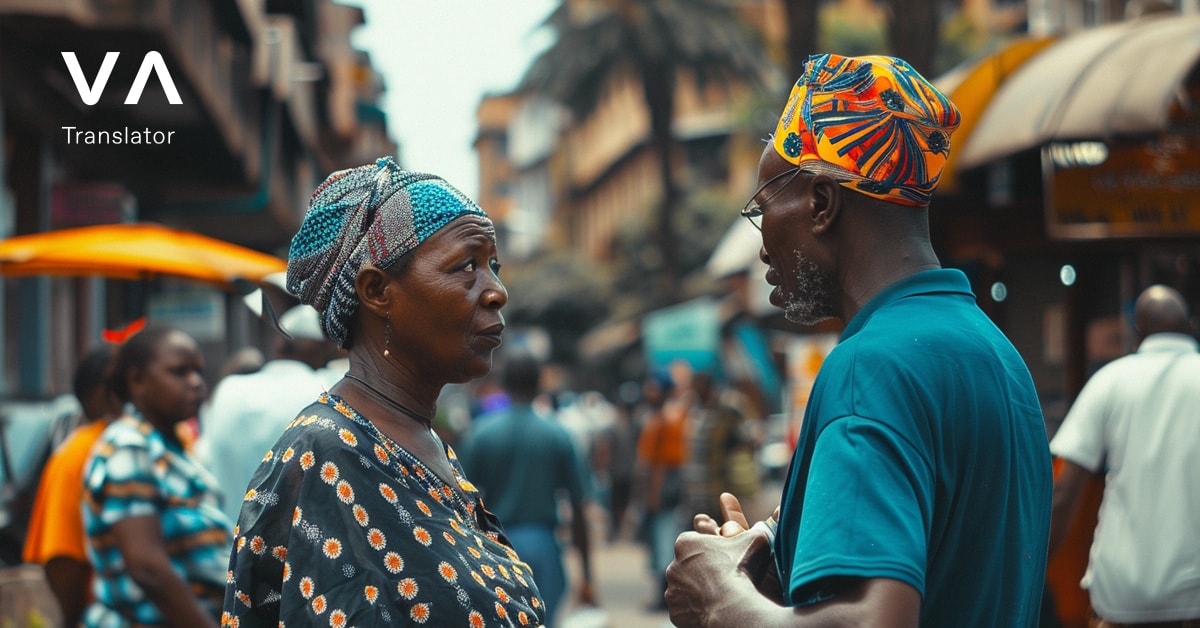 Un hombre y una mujer mayores conversando en una calle concurrida con ropa colorida africana y gente al fondo.