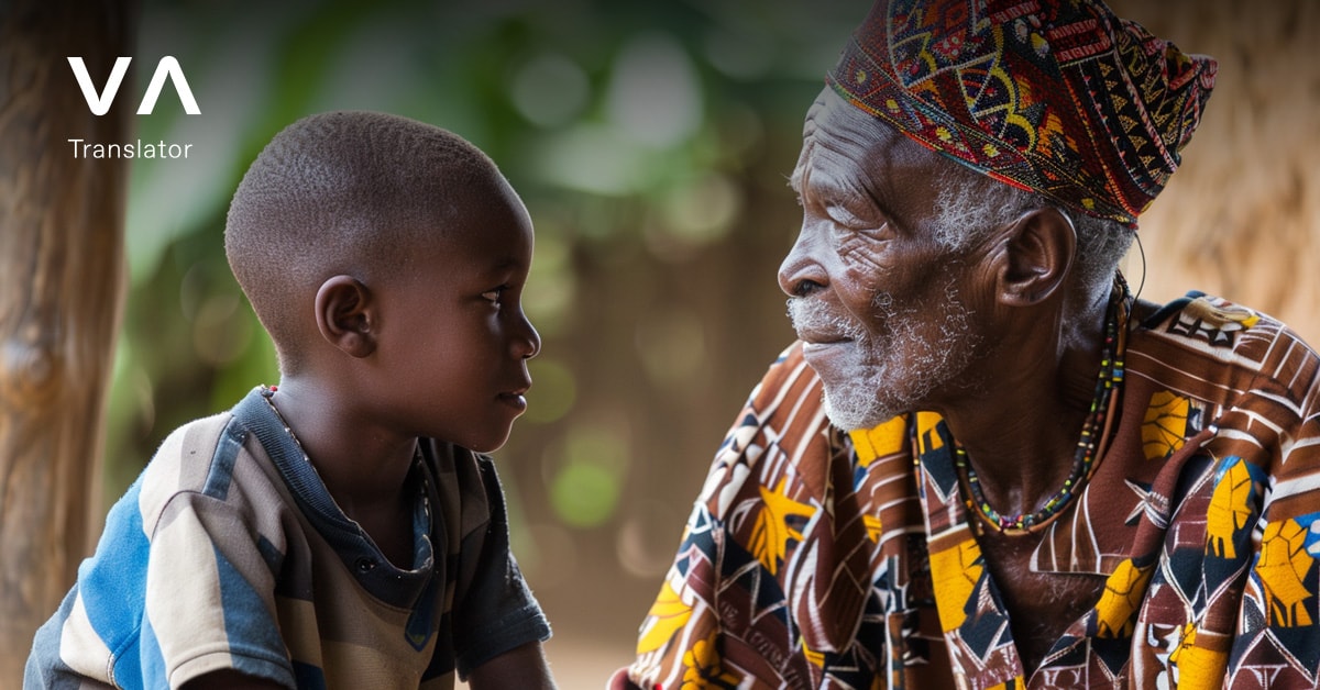 Un hombre mayor con atuendo tradicional africano colorido sentado y hablando con un niño, ambos mirándose atentamente.