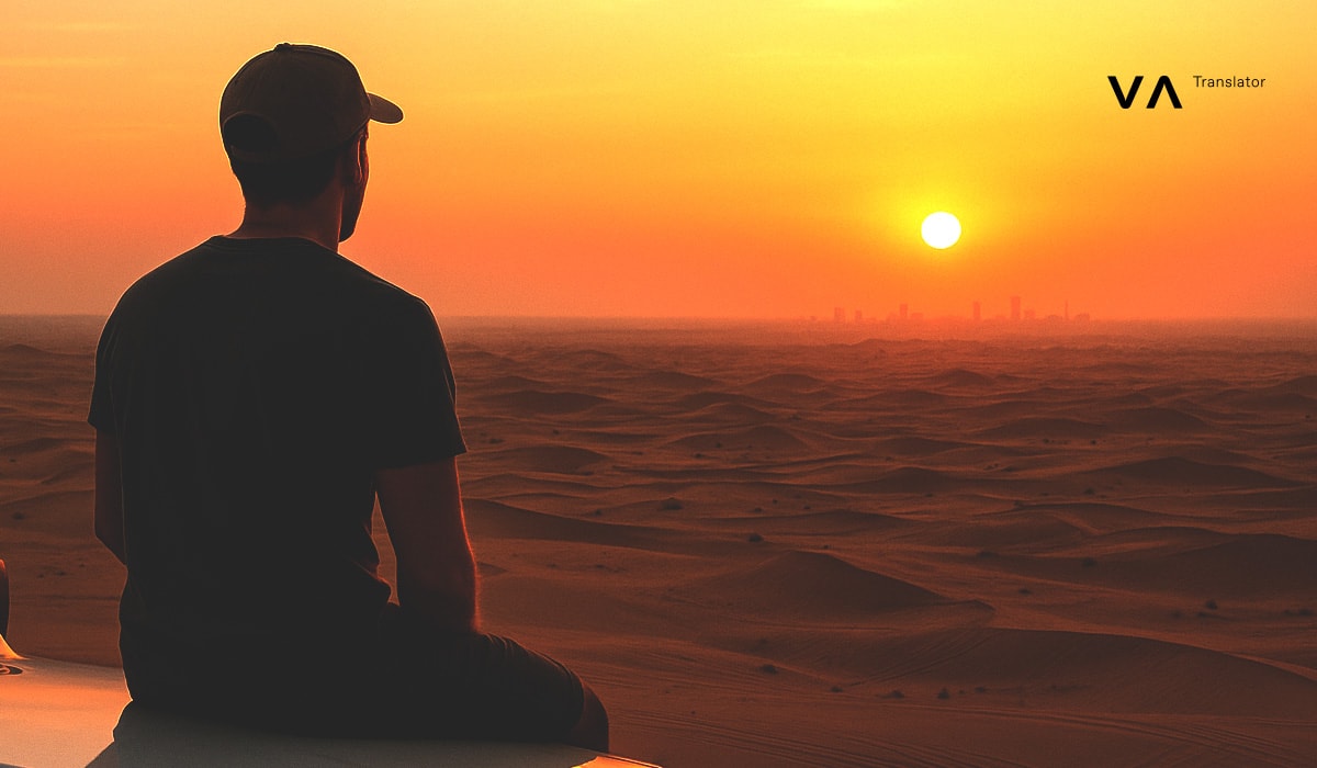 Un hombre está sentado de espaldas en el desierto al atardecer, contemplando en la lejanía un horizonte de dunas y la silueta de una ciudad, con el logotipo de Vasco superpuesto.