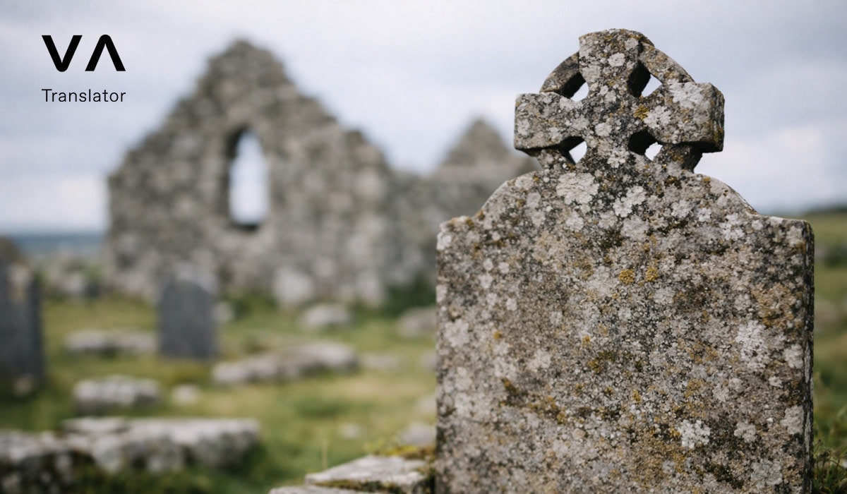 Lápida con cruz celta erosionada cerca de antiguas ruinas de piedra