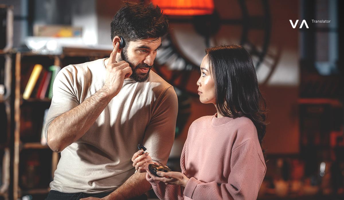 Un hombre y una mujer utilizan auriculares con traductor de IA para una conversación multilingüe en tiempo real.