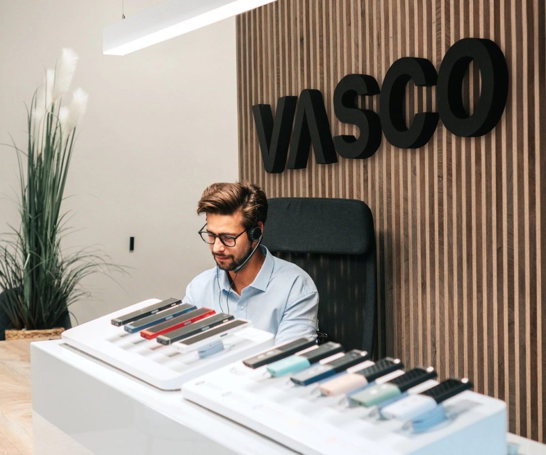 Un empleado del servicio de atención al cliente está sentado en un escritorio y exhibe varios traductores VA  en varios colores, con un gran letrero con la palabra 