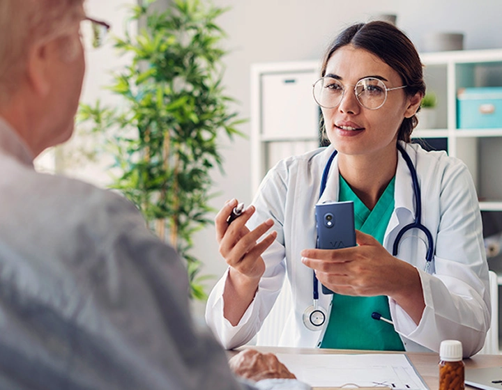 Una doctora sostiene el traductor V4 y habla con un paciente durante la consulta.