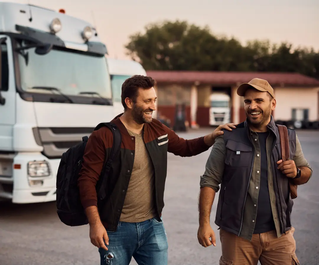 dos hombres de buen humor en un estacionamiento se alejan de los camiones estacionados en el fondo